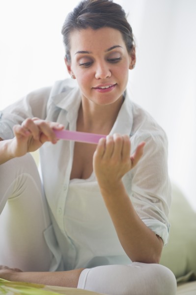 Attractive young woman filing nails.