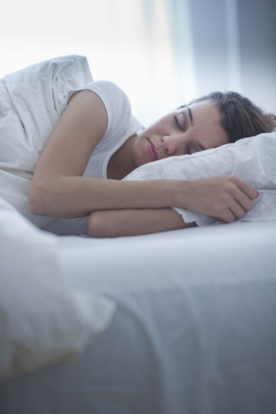 Happy young woman sleeping in bed.