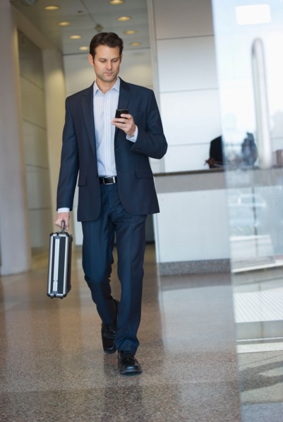 Businessman leaving office and using PDA.