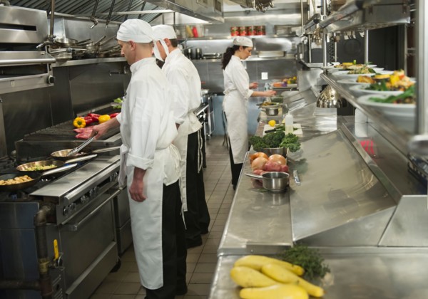 Chefs preparing food in kitchen.