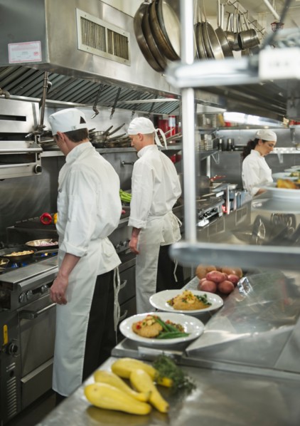 Chefs preparing food in kitchen.