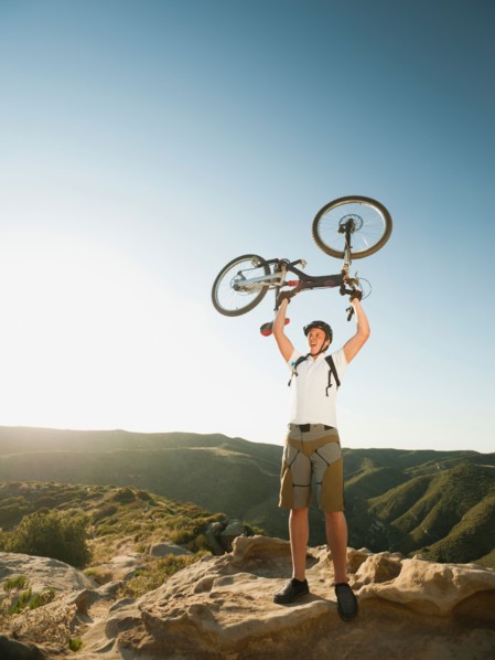 USA, California, Laguna Beach, Mountain biker on top of hill holding up his bike.
