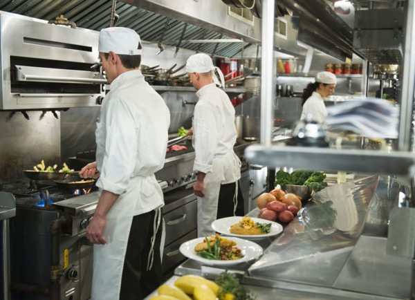 Chefs preparing food in kitchen.