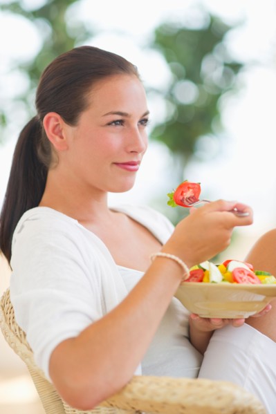Portrait of young woman eating salad.