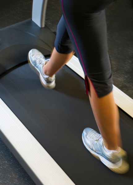 Low section of woman walking on treadmill.