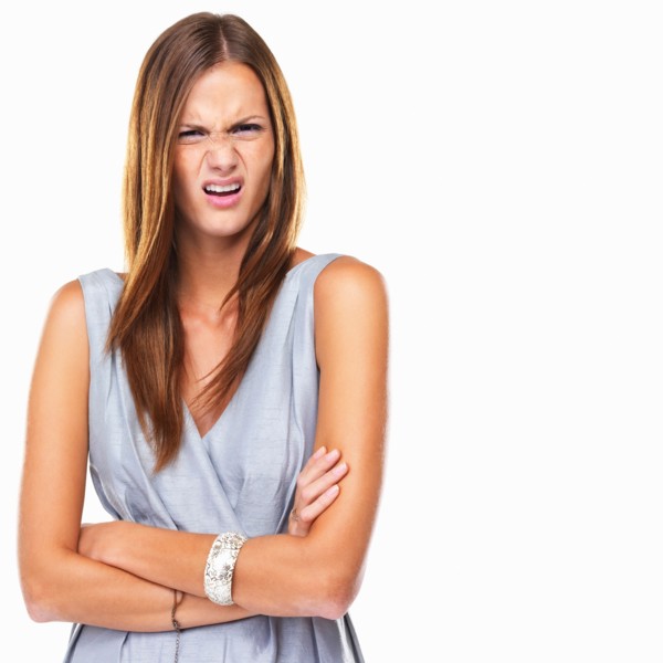 Portrait of young distressed woman standing with hands folded. Photo: momentimages