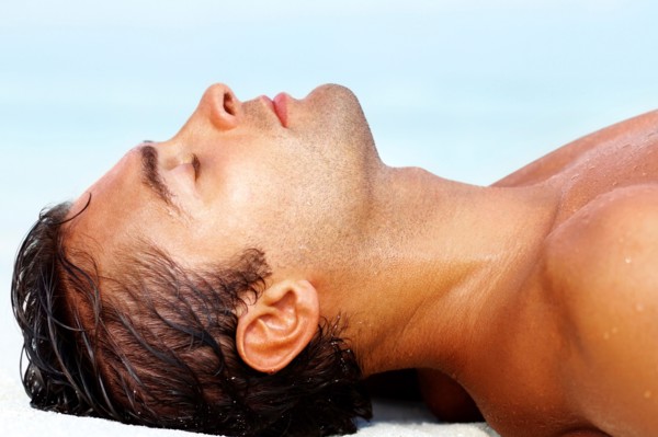 Profile of young guy lying on the beach. Photo : momentimages