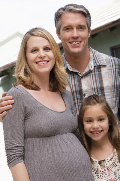 Pregnant mother, father and daughter (6-7) posing for portrait. Photo : Rob Lewine