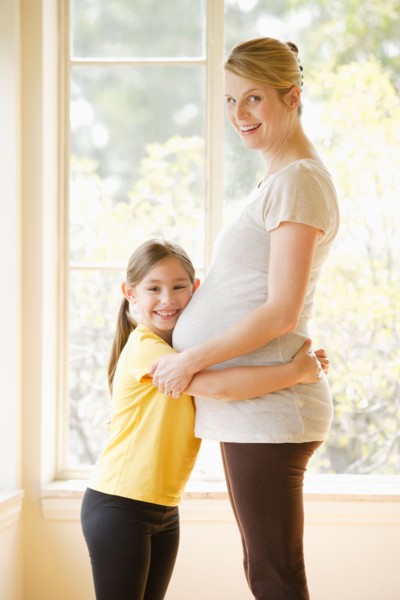 Daughter (6-7) embracing pregnant mother. Photo : Rob Lewine