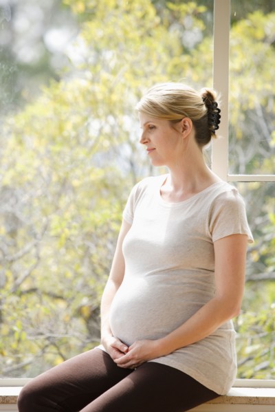Mid adult pregnant woman sitting on porch. Photo : Rob Lewine