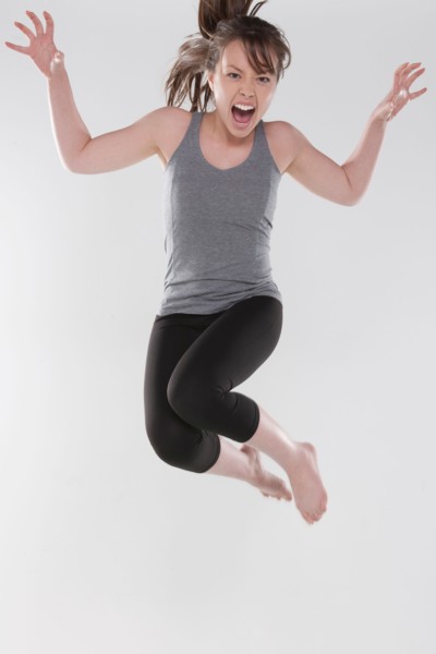 Portrait of young woman jumping, studio shot. Photo : Rob Lewine