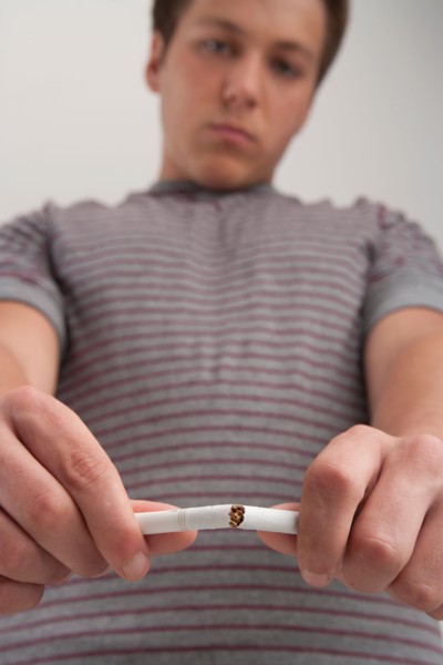 Teenage boy (16-17) breaking cigarette, studio shot. Photo: Rob Lewine