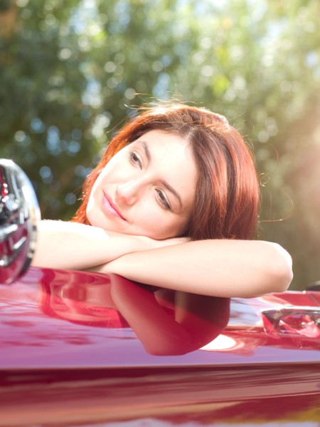 Smiling young woman in convertible car. Photo : db2stock