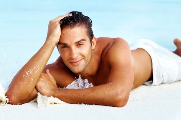 Smart young man relaxing on beach. Photo : momentimages