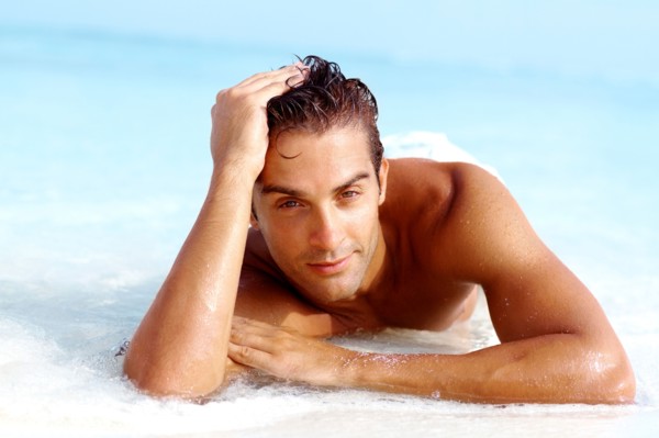 Portrait of attractive young man relaxing on beach. Photo : momentimages
