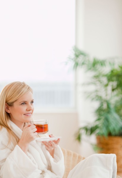 Young woman in bathrobe drinking tea. Photo : Jamie Grill