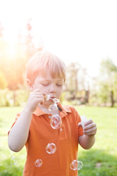 Boy (2-3) blowing bubbles in park. Photo : Take A Pix Media