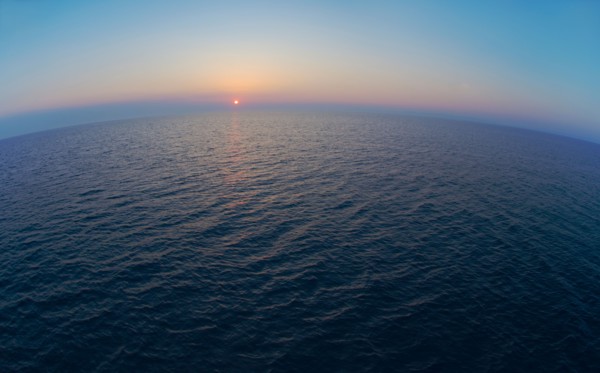 Aerial view of horizon over sea at sunrise.