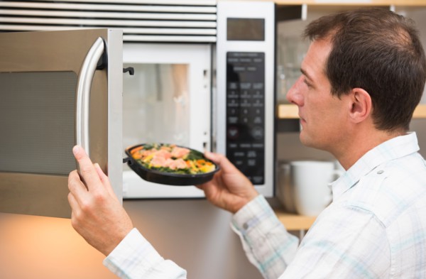 Man inserting meal in microwave oven.