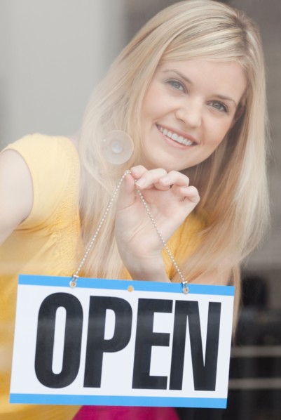 Portrait of young woman hanging sign in window. Photo : Jamie Grill