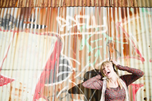 USA, Brooklyn, Williamsburg, Portrait of woman with headphones against graffiti wall. Photo : Jamie