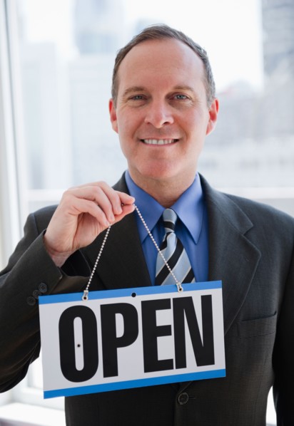 Businessman holding open sign. Photo : Jamie Grill
