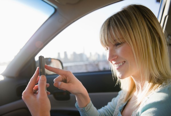 USA, Brooklyn, Williamsburg, Woman using smart phone in car. Photo : Jamie Grill