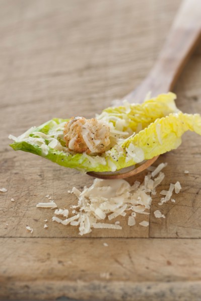 Fresh caesar salad on wooden spoon.
