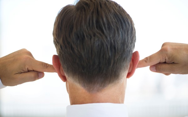Businessman plugging ears.