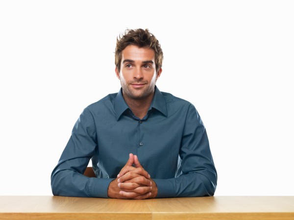 Smiling business man sitting at table with hands clasped. Photo : momentimages