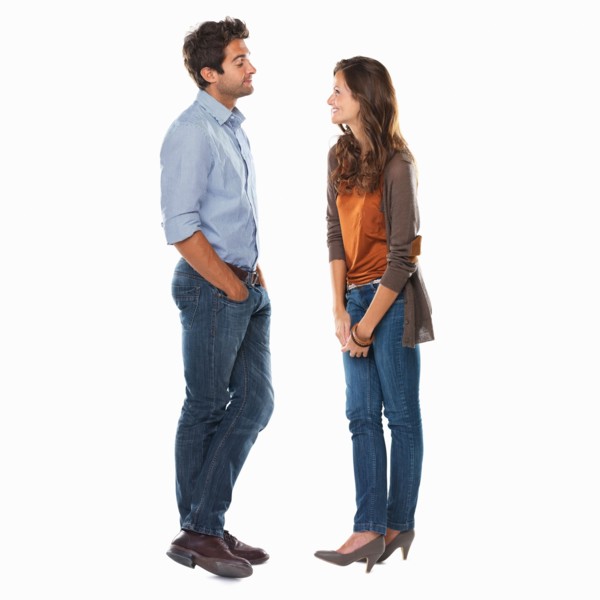 Studio shot of young couple standing face to face and smiling. Photo: momentimages