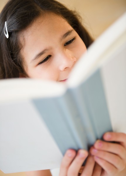 Portrait of girl (10-11) reading book. Photo : Jamie Grill