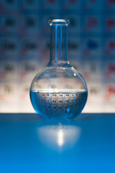 Beaker with periodic table in laboratory.