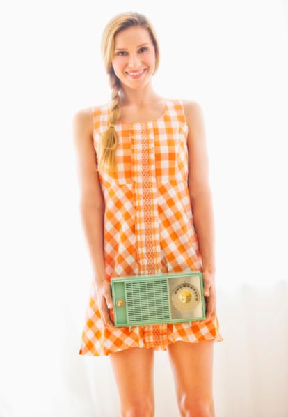 Studio portrait of young woman holding antique radio.