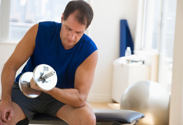 Mature man lifting weights in gym.