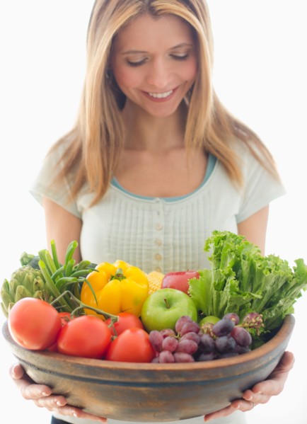 Woman holding bowl of organic fruit and vegetables.