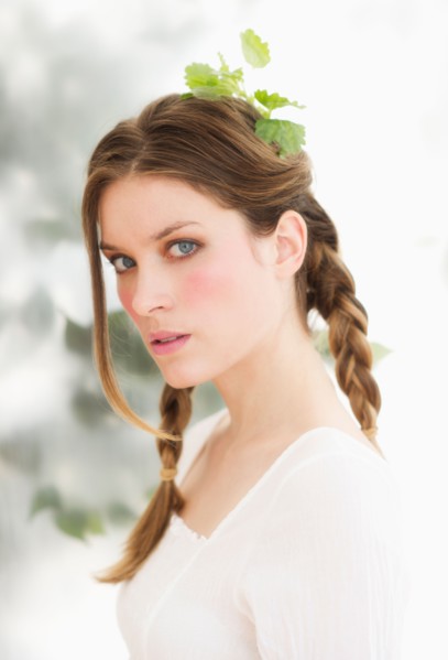 Studio portrait of young woman with leaves in hair.