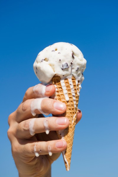 Hand holding melting ice cream.