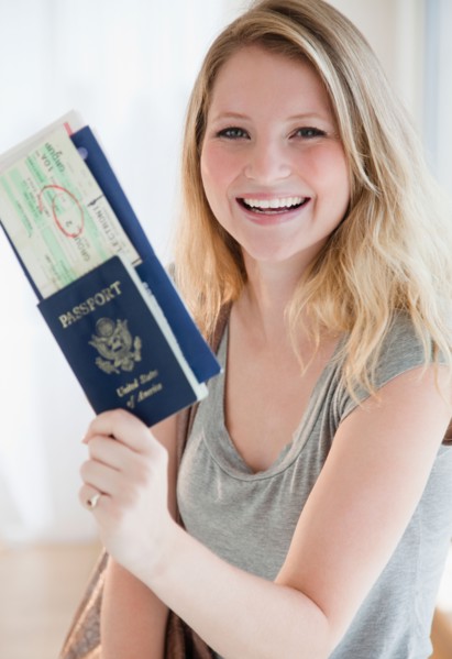 Young woman holding passports and plane tickets. Photo: Jamie Grill