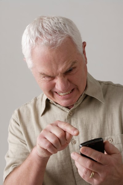 Portrait of angry senior man with mobile phone, studio shot. Photo : Rob Lewine