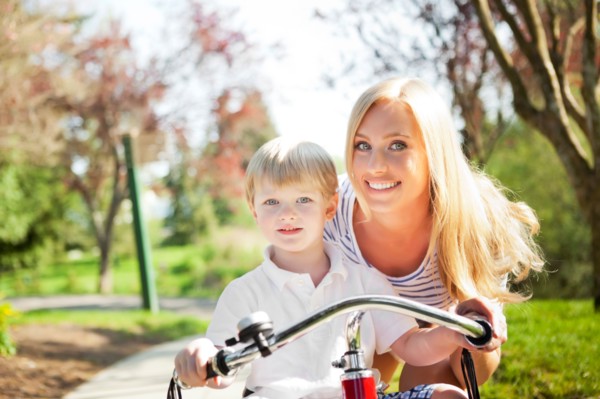 Mother and son (2-3) riding tricycle in park. Photo : Take A Pix Media