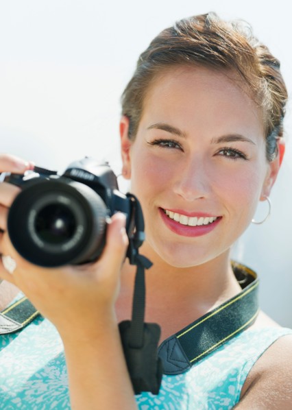 Portrait of young woman taking pictures with camera.