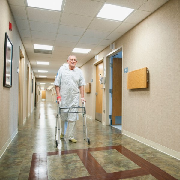 Senior man in hospital walking with walker.