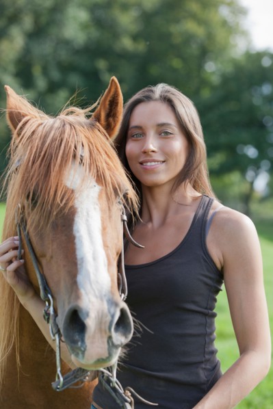 Portrait of young woman with horse in field. Photo : Jan Scherders