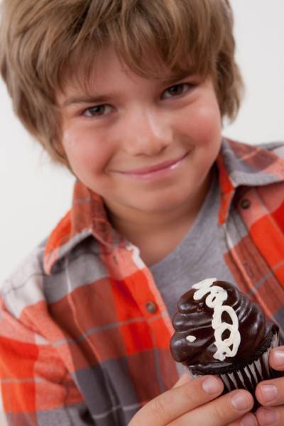 Studio portrait of boy (8-9) holding cake. Photo : Rob Lewine