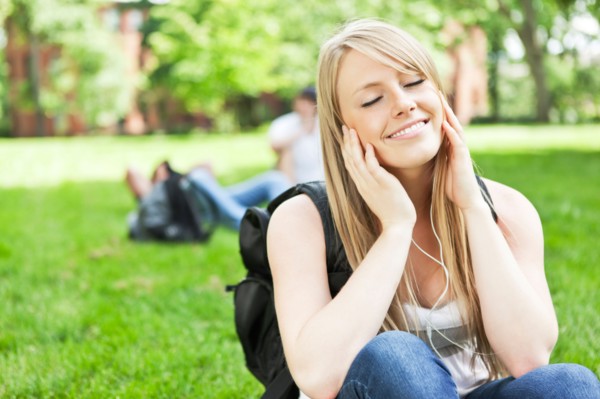 Woman listening to mp3 player in park. Photo : Take A Pix Media