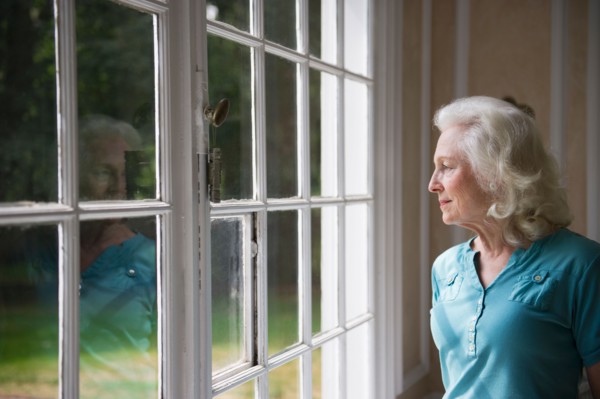 Senior woman looking through window.