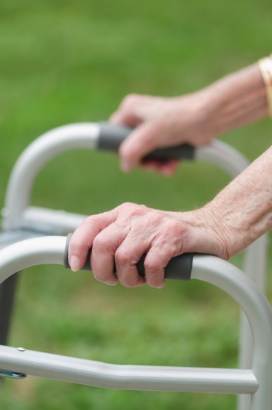 Senior walking with walker, close-up of hands.