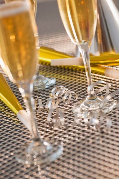 Flutes with champagne, party horn blowers and paper party hats. Photo: Daniel Grill