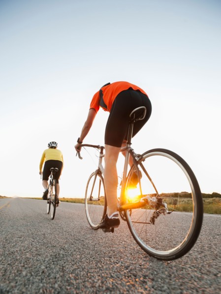 Mid adult couple cycling on empty road. Photo: Erik Isakson